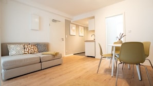 Un salon moderne avec un canapé, des fauteuils et une petite table à manger.