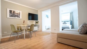 Un salon moderne comprenant un coin repas, un téléviseur à écran plat et un canapé agrémenté d’un coussin à motifs.