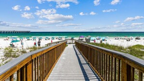A wooden boardwalk leading to a beach with umbrellas and people. - ☀️🌊 🏖️Stunning 5 Star Gulf Front 5th Floor, Regency Building 🌊☀️🏖️ (Navarre)