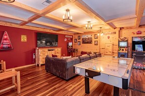A cozy room with a pool table, wooden ceiling beams, and a red wall with various decorations.