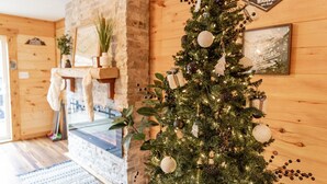 Ein gemütliches Zimmer mit Holzvertäfelung, Kamin und festlich geschmücktem Weihnachtsbaum.