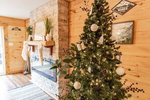 Une pièce chaleureuse avec un décor intérieur en bois, une cheminée et un sapin de Noël décoré.