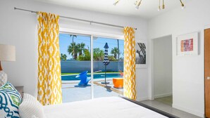 Une chambre d’hôtel avec un lit, une vue sur une piscine et une porte donnant sur l’extérieur.