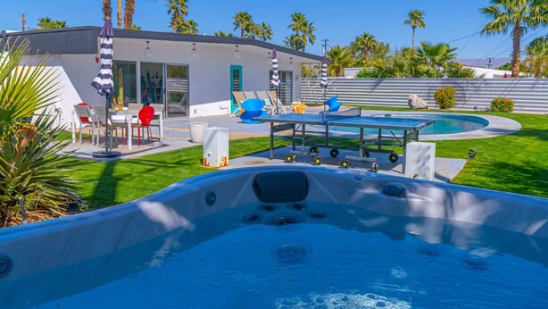 Une maison moderne dotée d’une piscine, d’un espace salon extérieur et d’un jacuzzi.