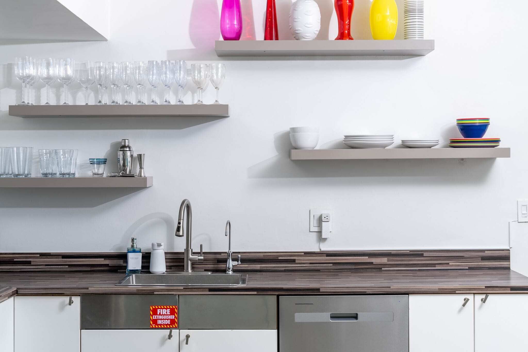 A modern kitchen with stainless steel appliances, a built-in sink, and a fire extinguisher sign.