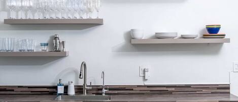 A modern kitchen with stainless steel appliances, a built-in sink, and a fire extinguisher sign.