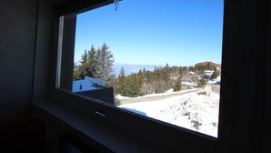 A window with a view of a snowy landscape, trees, and buildings in the distance. - 300m from resort center, 3rd floor, terrace, balcony, tv, 29m², Chamrousse (Chamrousse)