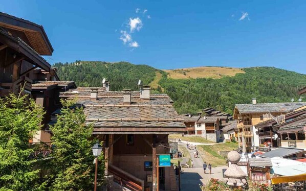 A traditional wooden building with a sloped roof, a sign indicating a restaurant, and a view of a mountainous landscape.