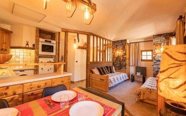 Experience a traditional room with a wooden-framed bed, dining table, and kitchen area.