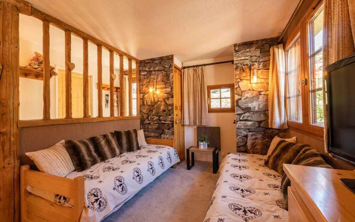 Una habitació acollidora amb dos llits de fusta, parets de pedra i una llar de pedra.