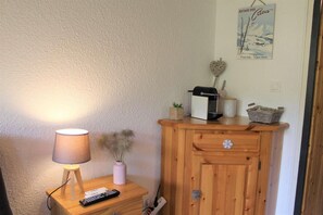 Cozy retreat with a wooden cabinet, lamp, and potted plant, perfect for relaxation.