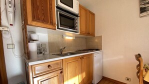 Une cuisine compacte avec des meubles en bois, un four à micro-ondes, un évier et un lave-vaisselle.