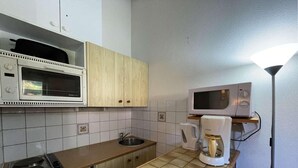 A compact kitchen with a microwave, coffee maker, and a stove.