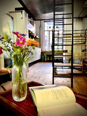 A room with a wooden floor, a bookshelf, and a window with curtains.