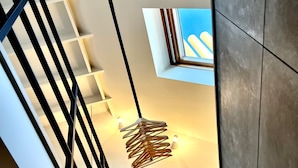 A modern interior with a staircase, a hanging light fixture, and a view through a window. - Agelandkaai.be (Ghent)
