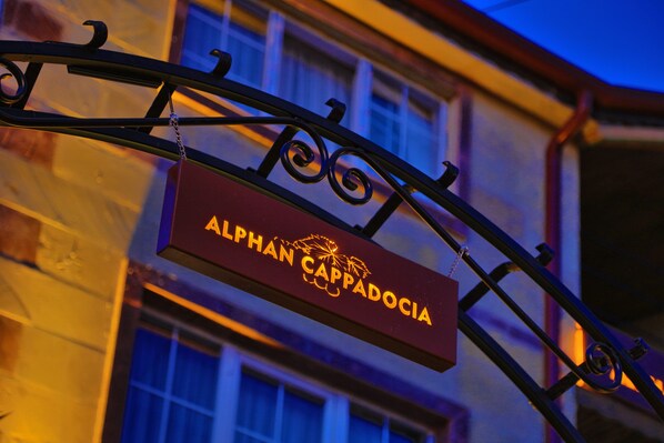 Uma placa com o nome 'ALPHAN CAPPADOCIA' pendurada em uma estrutura de ferro forjado.