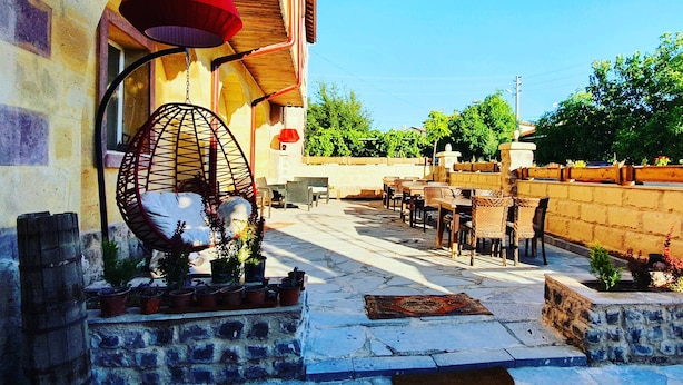 An outdoor patio with stone flooring, wicker chairs, and tables.