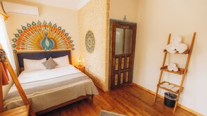 A bedroom with a bed, a wooden ladder, a wall with a decorative pattern, and a door.