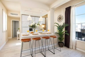 Een moderne keuken met een centraal eiland, barstoelen en een groot raam met gordijnen.