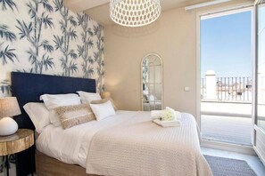 A bedroom with a bed, bedside lamps, a mirror, and a view of the outside. - Penthouse Lorena (Granada)