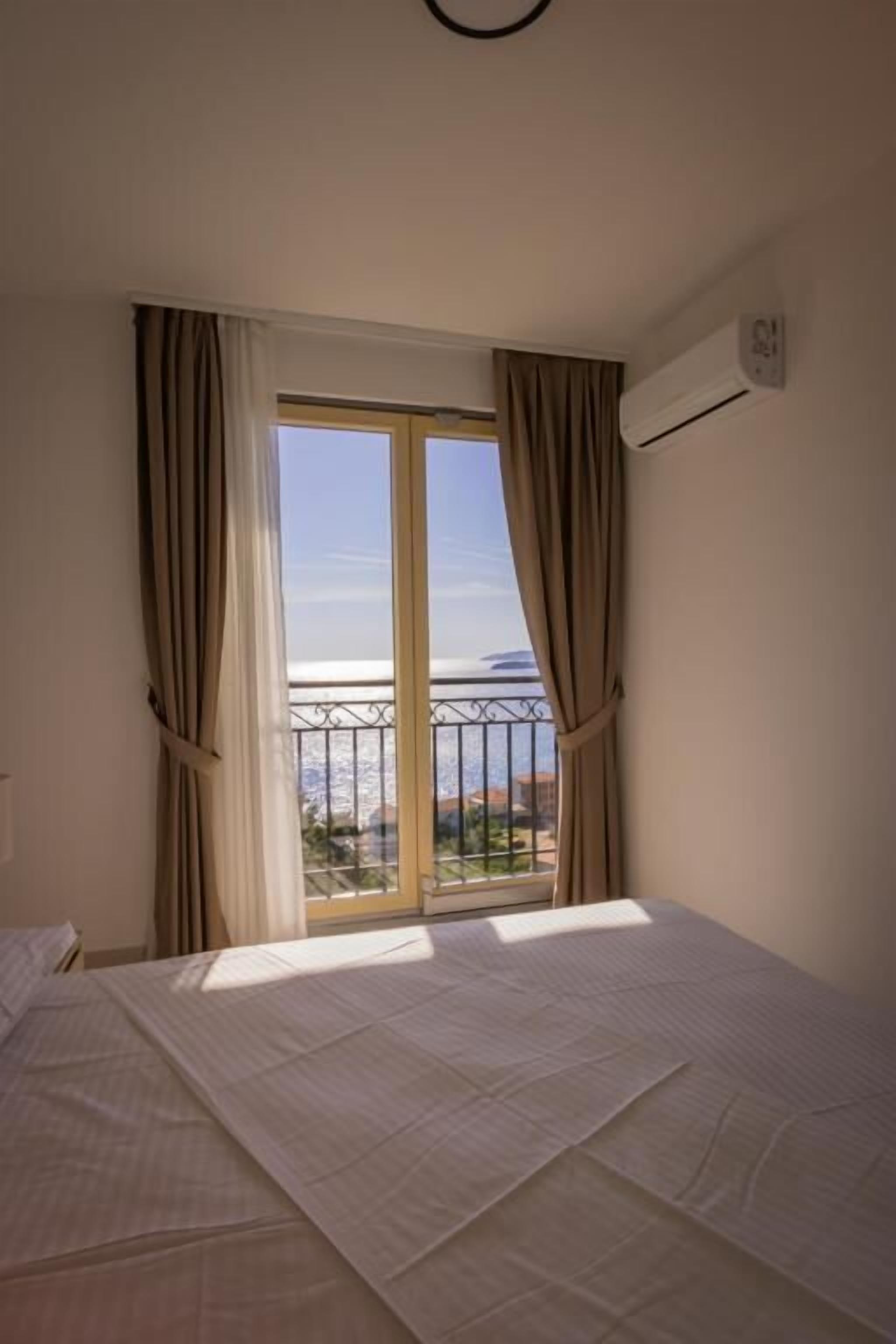 Een hotelkamer met een bed, een raam met gordijnen en een airconditioning.