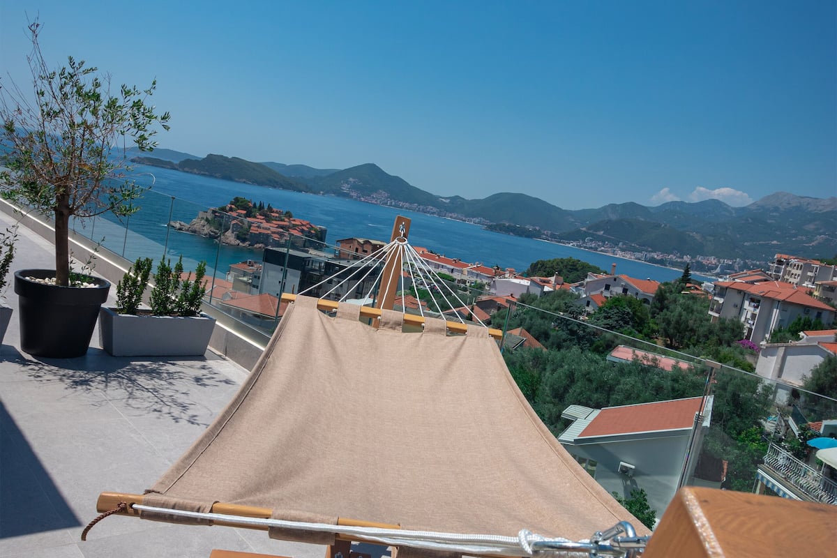Un hamac sur une terrasse sur le toit, avec vue sur une ville côtière et des montagnes.