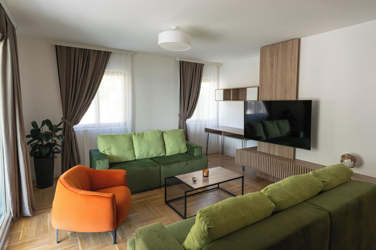 Un salon moderne avec un canapé vert, un fauteuil orange et une table basse en bois.