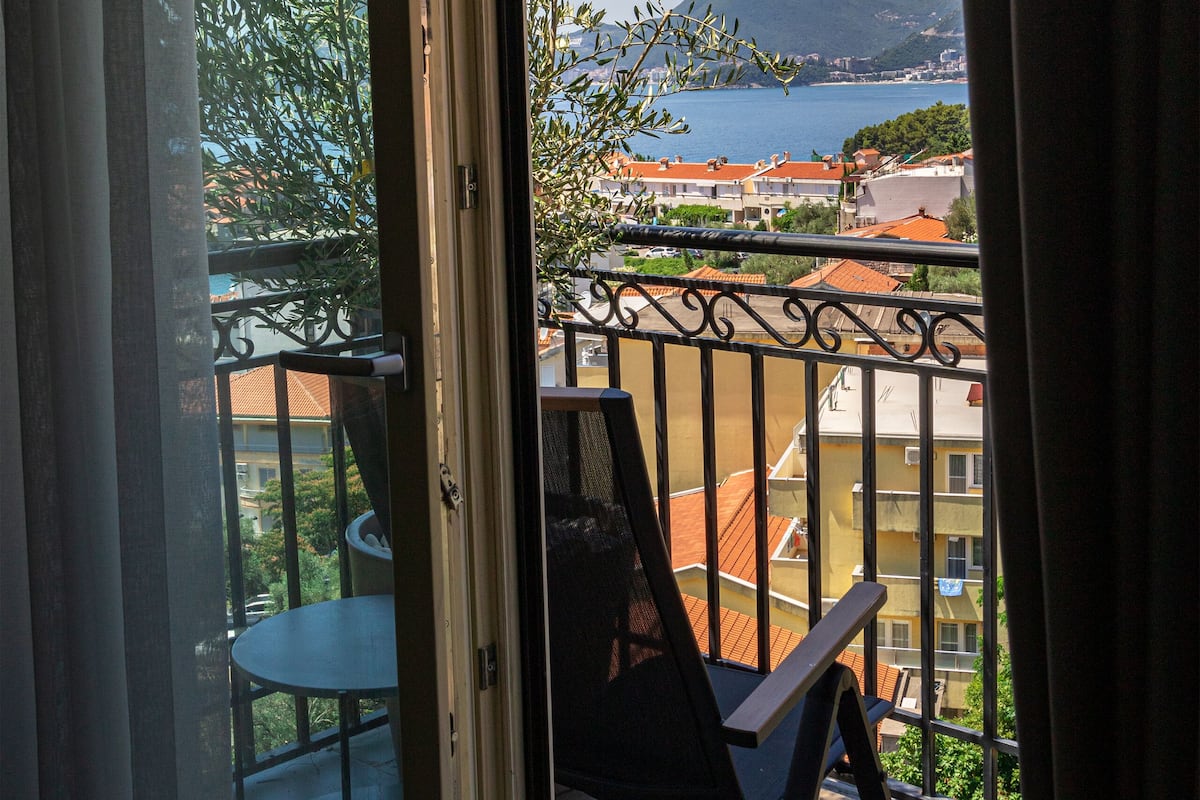 Un balcon donnant sur une ville côtière, avec une chaise et une table.