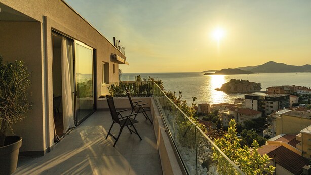 A balcony with a view of the sea and a mountain, featuring a table and chairs. - Vertmont Villa (Sveti Stefan)
