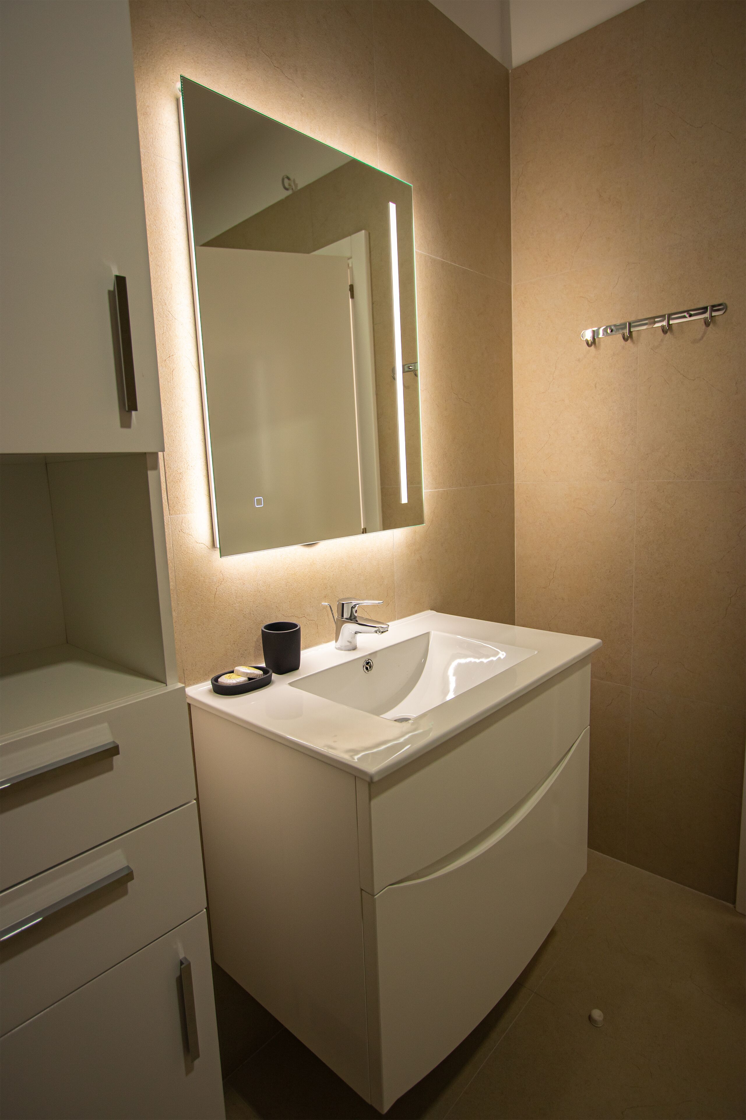 Un baño moderno con un espejo grande, un lavabo y un perchero para toallas.