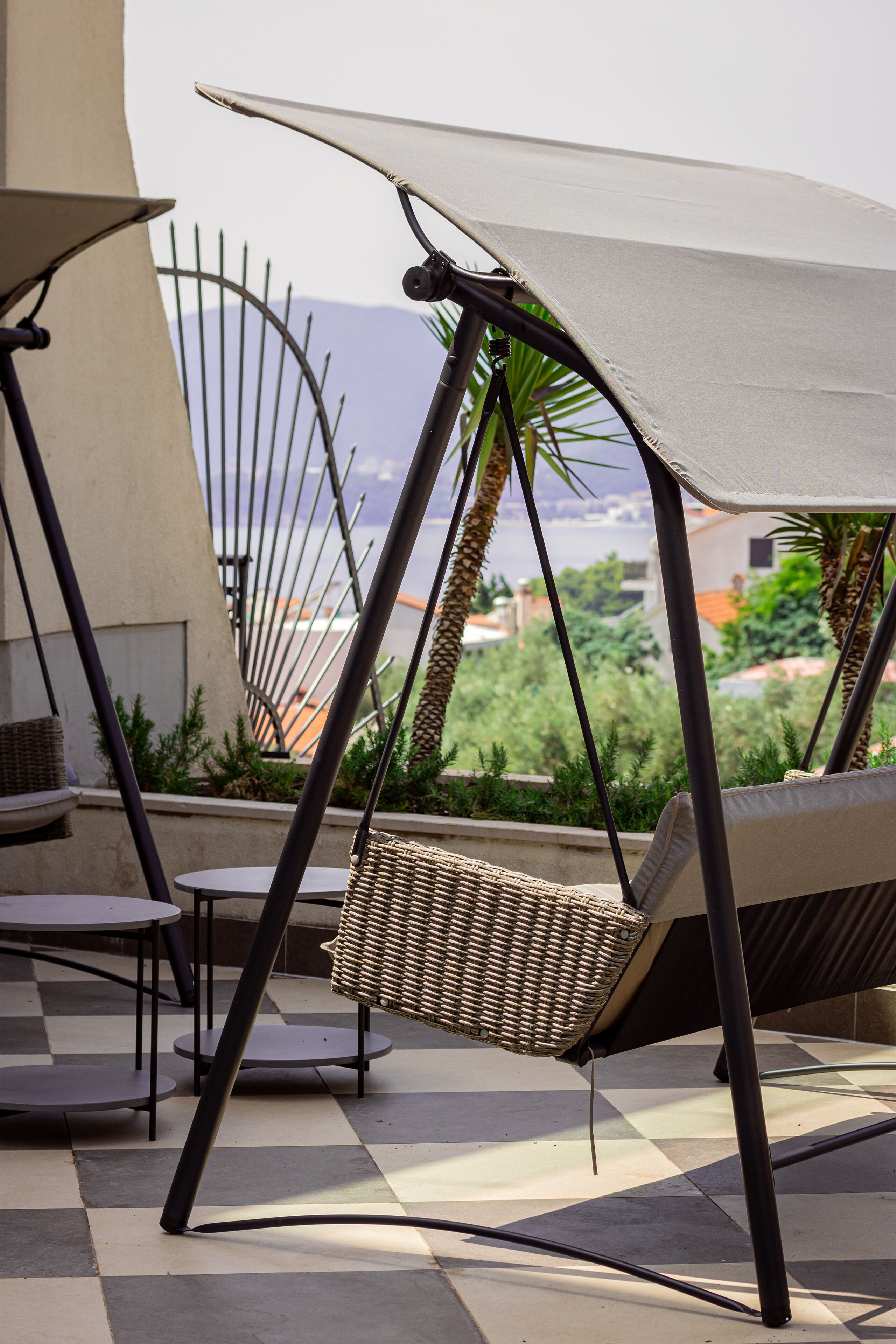 A patio area with a wicker chair, a table, and a swing chair with a canopy.