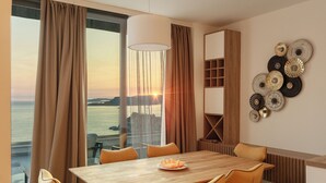 A dining area with a wooden table and orange chairs, a view of the sea, and a wall with decorative plates. - Vertmont Villa (Sveti Stefan)