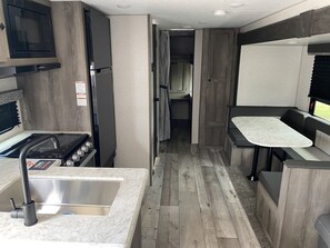Efficient kitchenette with a stainless steel sink, gas stove, and microwave, perfect for self-contained cooking and dining.