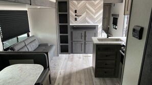 Ein kompaktes Wohnmobil-Interieur mit einer Küchenzeile, einer Sitzecke und einem kleinen Esstisch.