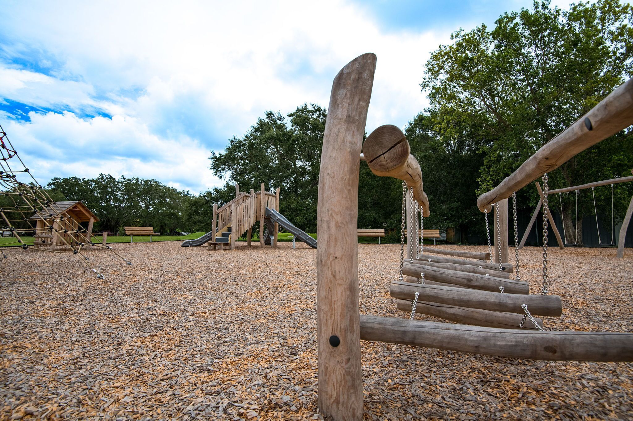 Une aire de jeux avec des structures d’escalade en bois et un toboggan.