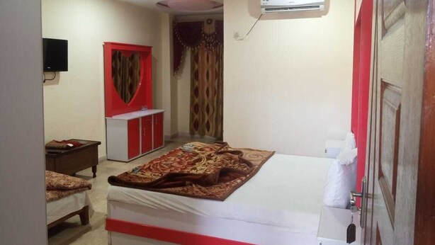 A bedroom with a bed, a TV, a wardrobe, and an air conditioner. - Hotel Continental (Rawalpindi)