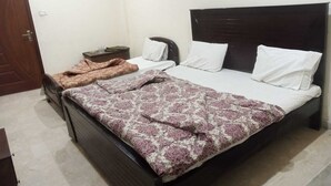 A bedroom with a dark wooden bed, white pillows, and a patterned bedspread. - Hotel Continental (Rawalpindi)
