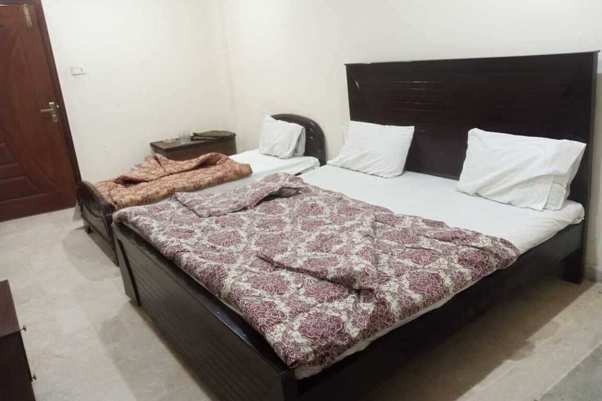 A bedroom with a dark wooden bed, white pillows, and a patterned bedspread.