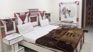 A hotel room with a bed, a bedside table, a mirror, and a wardrobe. - Hotel Continental (Rawalpindi)