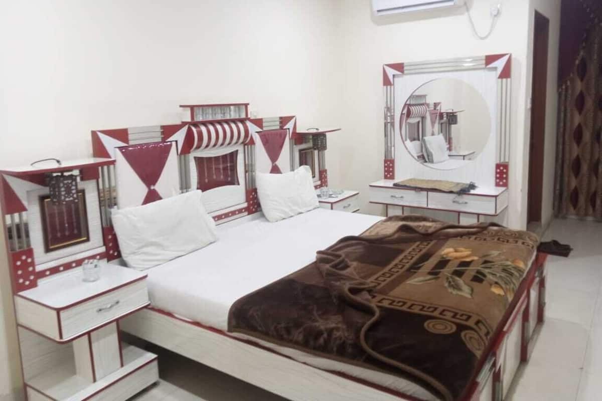 A hotel room with a bed, a bedside table, a mirror, and a wardrobe.