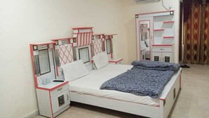 A bedroom with a bed, bedside tables, a wardrobe, and an air conditioning unit. - Hotel Continental (Rawalpindi)