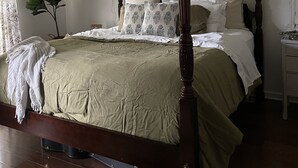 Un lit à baldaquin avec un cadre en bois, un ventilateur de plafond et un appareil de climatisation installé au-dessus.