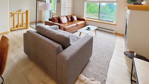 A spacious living room with a large gray sectional sofa, a small coffee table, and a wooden floor. - Riverside mountain getaway, million dollar views, ground access, attached garage (Silverthorne)