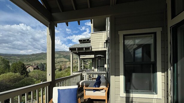 A wooden deck with a table set for dining, overlooking a scenic landscape. - Riverside mountain getaway, million dollar views, ground access, attached garage (Silverthorne)