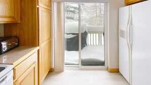 A kitchen with wooden cabinets, a white refrigerator, and a sliding glass door leading to a snowy deck. - Riverside mountain getaway, million dollar views, ground access, attached garage (Silverthorne)