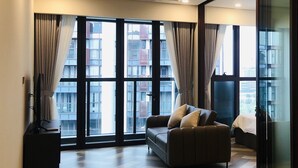 Amplia sala de estar con ventanas grandes, un sofá y un mueble para televisión.