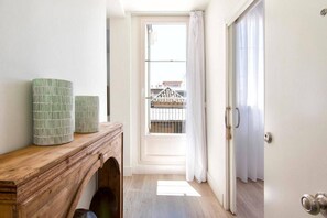 A narrow hallway leading to a balcony with a view of buildings.