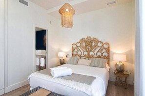 A bedroom with a large bed, two bedside lamps, a decorative headboard, and a hanging light fixture. - Alhambra Luxviews Apartment (Granada)