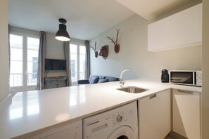 A compact kitchen with a built-in dishwasher, a microwave, and a sink. - Industrial Suite Apartment (Granada)
