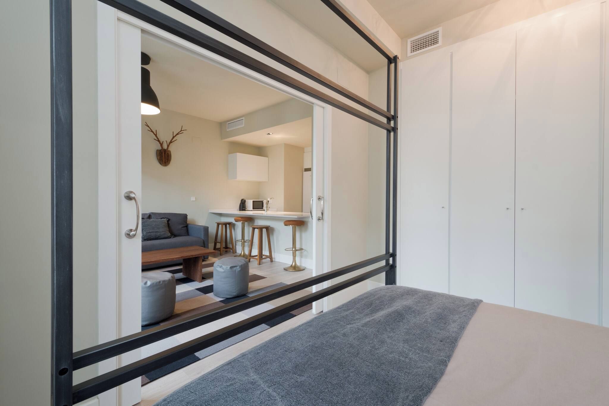 A modern room with a bed, a sofa, a dining area, and a wardrobe.